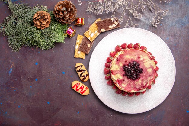 Draufsicht auf leckere fruchtige Pfannkuchen mit Gelee und Erdbeeren auf Dunkelheit