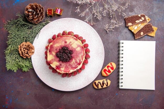 Draufsicht auf leckere fruchtige Pfannkuchen mit Gelee und Erdbeeren auf Dunkelheit