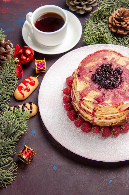 Kostenloses Foto draufsicht auf leckere fruchtige pfannkuchen mit tasse tee im dunkeln