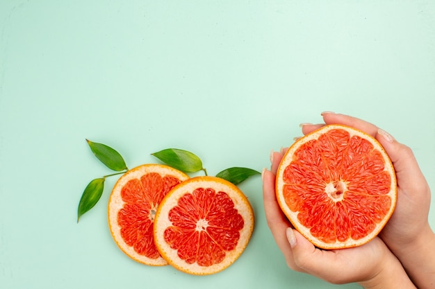 Kostenloses Foto draufsicht auf leckere grapefruits, die auf der hellblauen oberfläche saftig geschnitten wurden