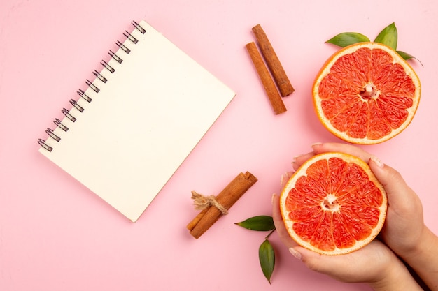 Draufsicht auf leckere Grapefruits-Fruchtscheiben mit Zimt auf der rosa Oberfläche