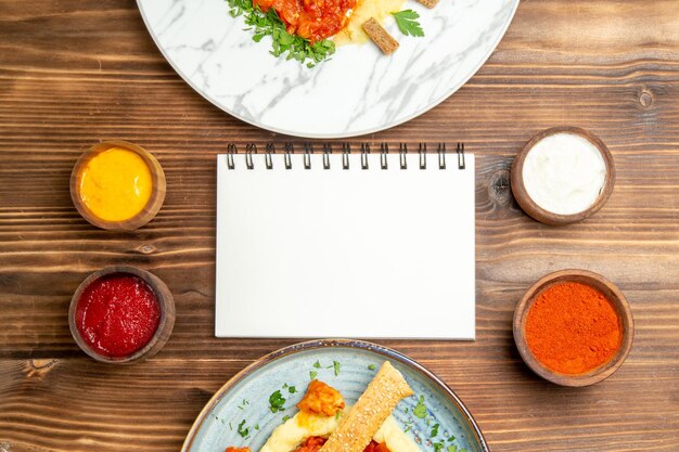 Draufsicht auf leckere Hähnchenscheiben mit Kartoffelpüree und Gewürzen auf braunem Tisch