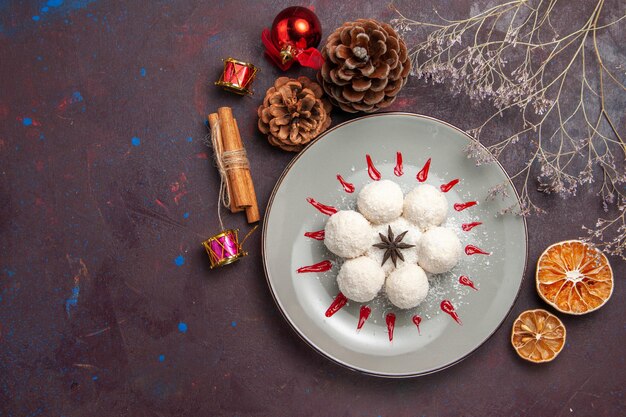 Draufsicht auf leckere Kokosbonbons rund geformt mit rotem Zuckerguss auf Schwarz