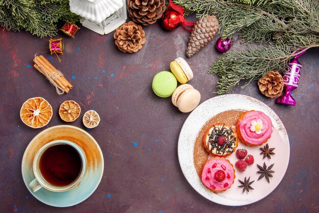 Draufsicht auf leckere Kuchen mit französischen Macarons und Tee auf Schwarz