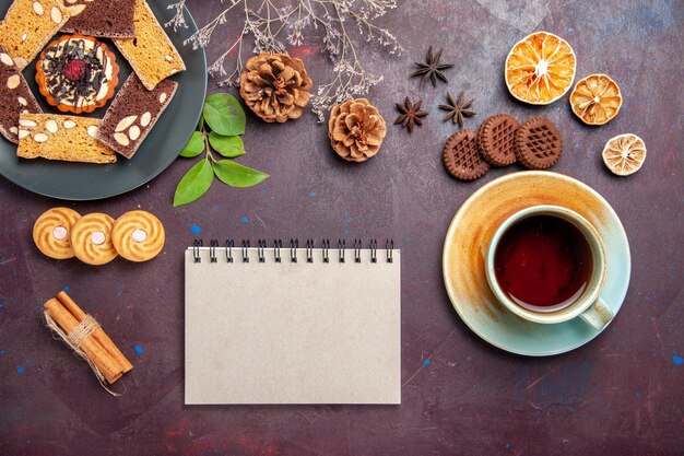 Draufsicht auf leckere Kuchenscheiben mit einer Tasse Tee auf Schwarz