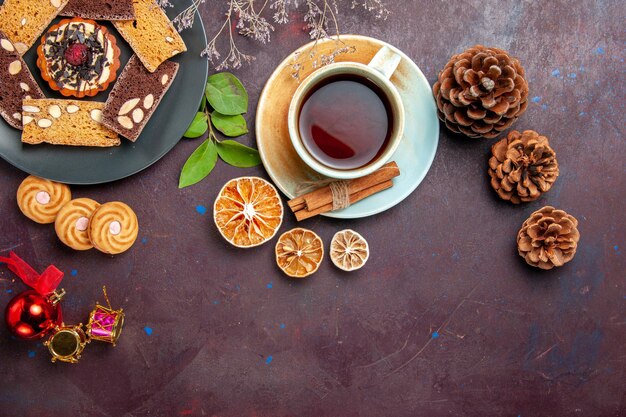 Draufsicht auf leckere Kuchenscheiben mit einer Tasse Tee auf Schwarz