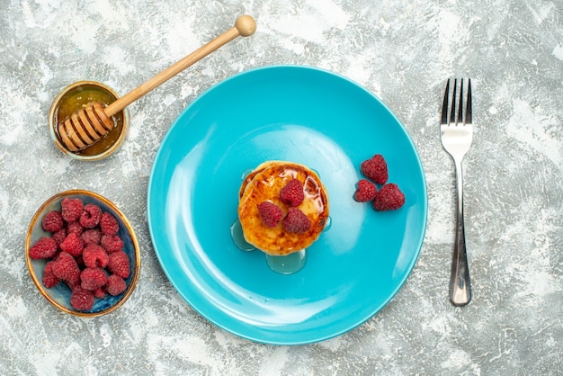 Draufsicht auf leckere Muffins mit Beeren und Honig auf heller Oberfläche