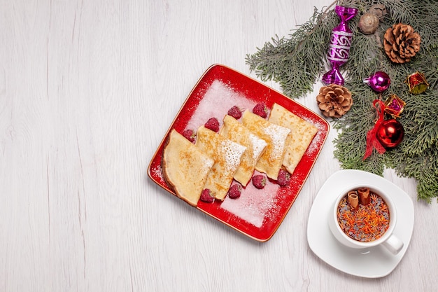 Draufsicht auf leckere Pfannkuchen mit Tasse Tee und Früchten auf Weiß