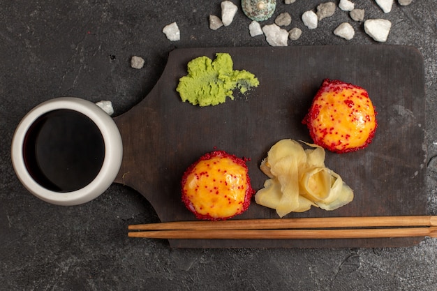 Draufsicht auf leckere sushi-mahlzeit fischröllchen mit fisch und reis zusammen mit soße auf grauer wand