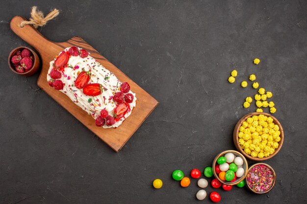 Draufsicht auf leckeren fruchtigen Kuchen mit Bonbons auf Schwarz