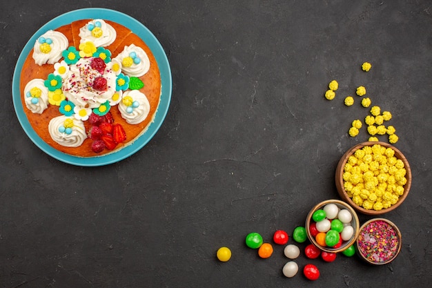 Draufsicht auf leckeren fruchtigen Kuchen mit Bonbons im Dunkeln