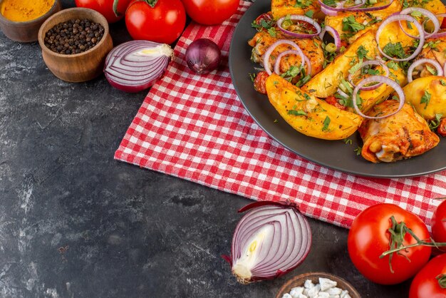 Draufsicht auf leckeres Hühnchenessen mit Kartoffeln und Grüns auf gefalteten rot gestreiften Handtuchgemüsegewürzen auf dunklem Farbtisch