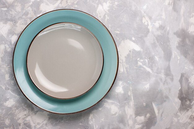 Draufsicht auf leere Teller aus Glas auf weißem Schreibtisch