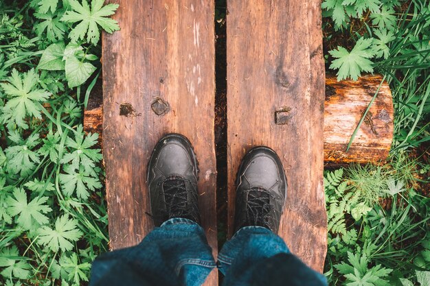 Draufsicht auf männliche Schuhe auf einem Holzweg in einem Wald