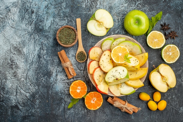 Draufsicht auf natürliche Äpfel Zitrone auf einem weißen Teller und Zimtlimetten Kumquats Orangen auf dunklem Tisch