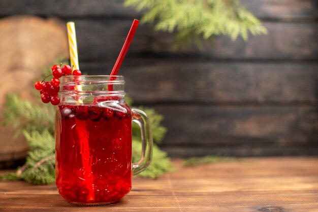 Draufsicht auf natürlichen organischen frischen Johannisbeersaft in einer Flasche, die mit Röhrchen auf der rechten Seite auf einem Holztisch serviert wird