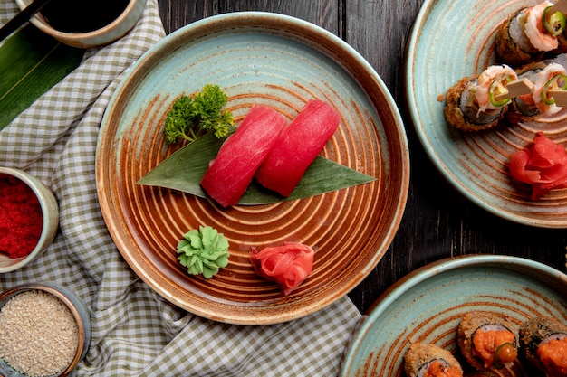 Draufsicht auf Nigiri-Sushi mit Thunfisch auf Bambusblatt, serviert mit eingelegten Ingwerscheiben und Wasabi auf einem Teller