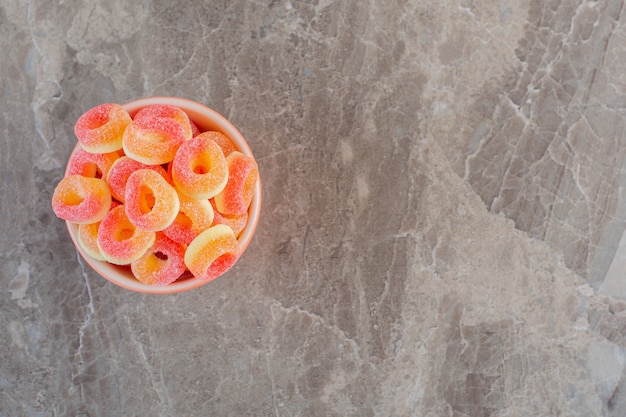 Draufsicht auf orangefarbene Bonbons in Ringform im Inneren der Schüssel.