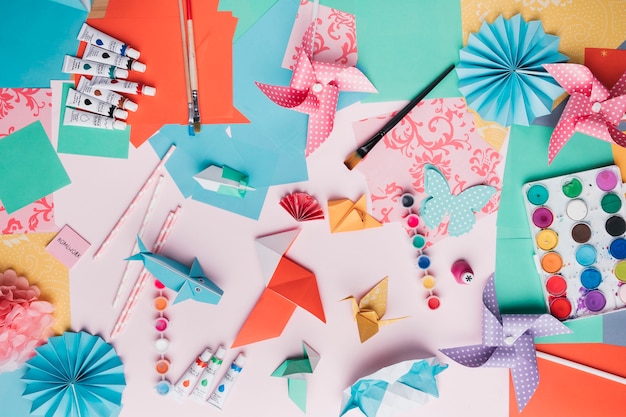 Draufsicht auf origami-handwerk; farbtube; pinsel; stroh und farbiges papier