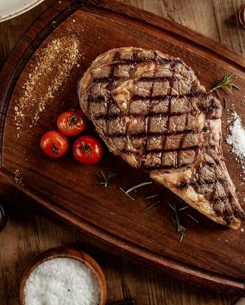 Draufsicht auf Rindersteak mit Salzkräutern und Kirschtomate an Bord serviert