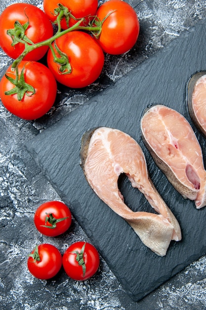 Kostenloses Foto draufsicht auf rohe fischscheiben auf tafeltomaten auf dem tisch