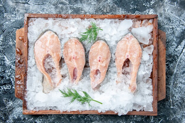 Draufsicht auf rohe Fischscheiben mit Eis auf Holzbrett auf dem Tisch