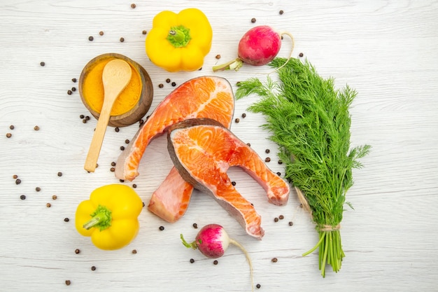 Draufsicht auf rohe Fleischscheiben mit Grüns und Paprika auf weißem Hintergrund