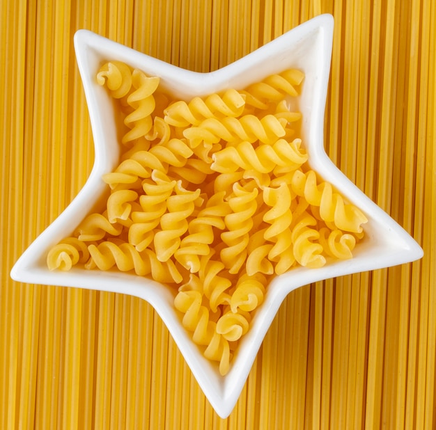 Kostenloses Foto draufsicht auf rohe spaghetti mit sternförmigen nudeln in einer schale
