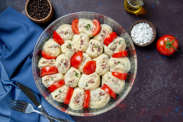 Draufsicht auf rohe Teigstücke mit Hackfleisch und Tomaten auf der dunklen Mahlzeit Küche Gericht Küche Foto Farbe Lebensmittel Salat