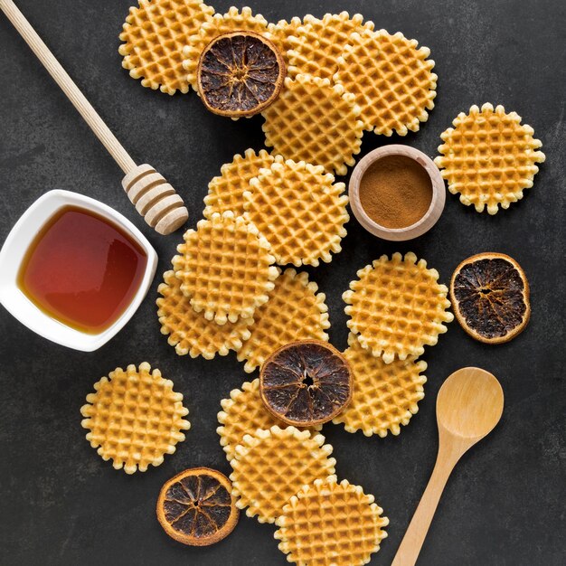 Draufsicht auf runde Waffeln mit Honigschöpflöffel und getrockneten Zitrusfrüchten