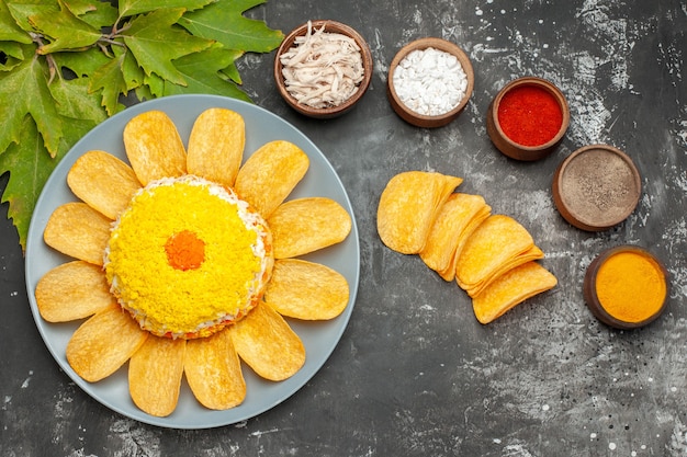 Draufsicht auf Salat mit Kräutern und Pommes links und Blätter rechts auf dunklem Hintergrund