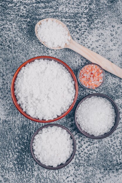 Draufsicht auf Salz in Glas, Schalen und Holzlöffel mit Himalaya-Salz