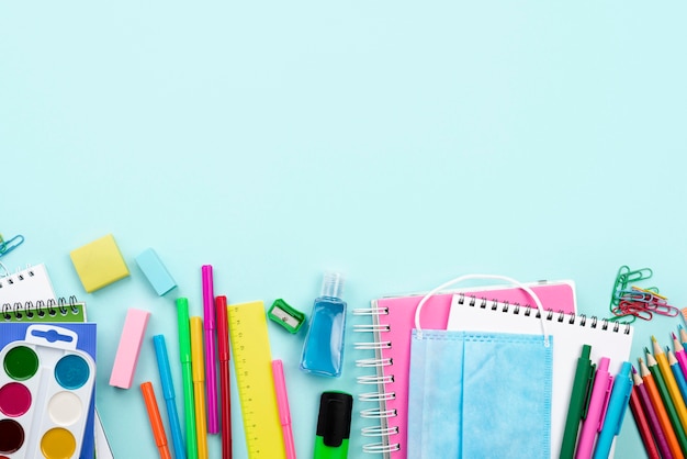 Draufsicht auf Schulbriefpapier mit medizinischer Maske und bunten Stiften