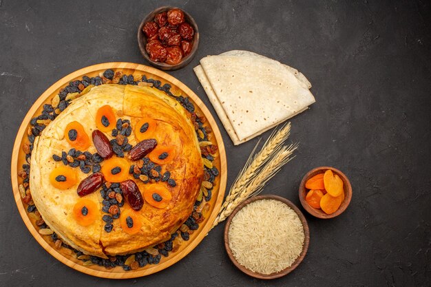 Draufsicht auf Shakh Plov köstliches Reismehl, das innerhalb des runden Teigs mit Rosinen auf der grauen Oberfläche gekocht wird