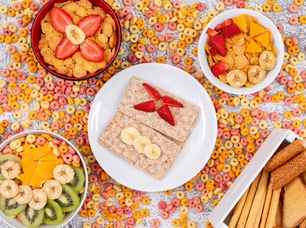 Draufsicht auf Toast mit Cornflakes und Früchten auf weißer Fläche horizontal