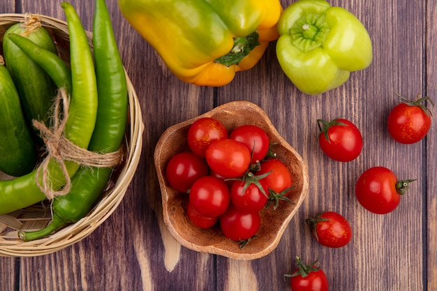 Draufsicht auf Tomaten in Schüssel und Paprika im Korb und auf Holzoberfläche