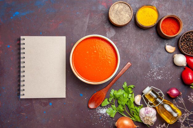 Draufsicht auf Tomatensuppe gekocht aus frischen Tomaten mit Gewürzen auf Schwarz