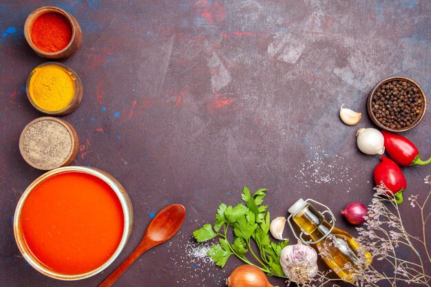 Draufsicht auf Tomatensuppe gekocht aus frischen Tomaten mit verschiedenen Gewürzen auf Schwarz