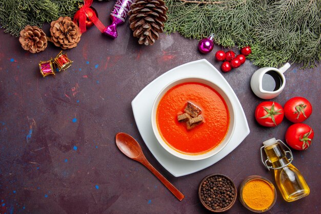 Draufsicht auf Tomatensuppe mit frischen Tomaten und Gewürzen auf Schwarz