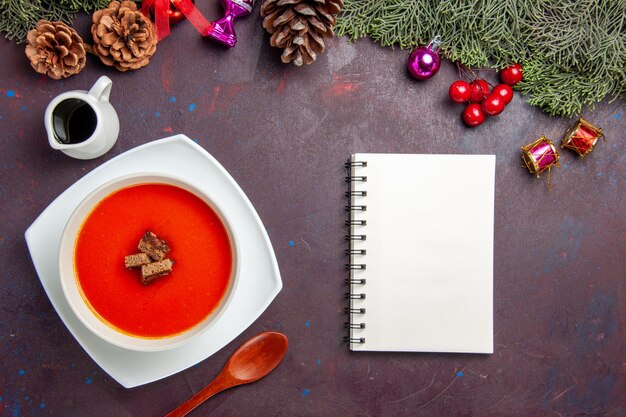 Draufsicht auf Tomatensuppe mit geschnittenem Brot im Inneren auf Schwarz