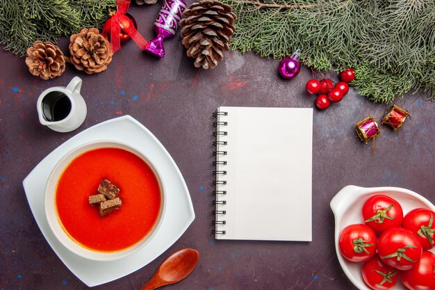 Draufsicht auf Tomatensuppe mit geschnittenem Brot im Inneren auf Schwarz