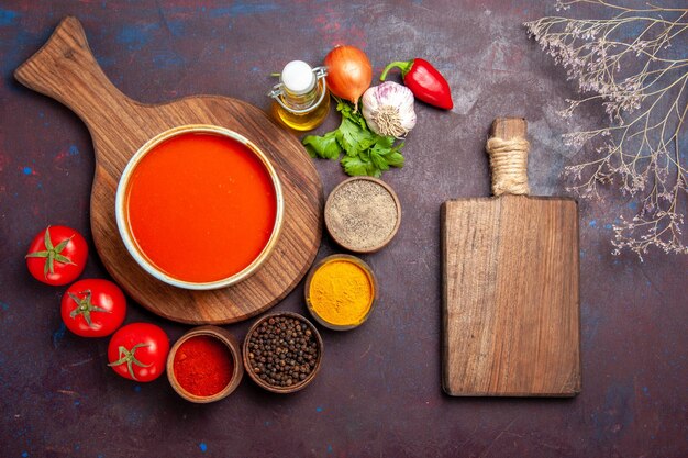 Draufsicht auf Tomatensuppe mit Gewürzen auf Schwarz