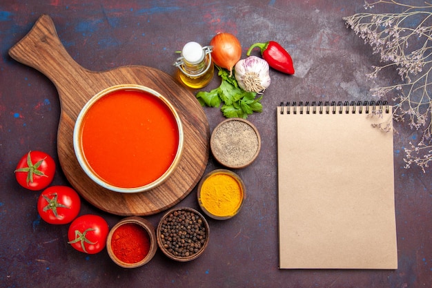 Draufsicht auf tomatensuppe mit gewürzen auf schwarz