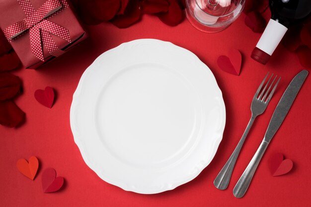 Draufsicht auf Valentinstagstisch mit Teller und Geschenk