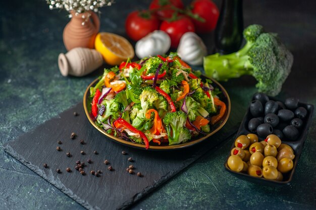 Draufsicht auf veganen Salat mit frischen Zutaten in einem Teller auf schwarzem Schneidebrett