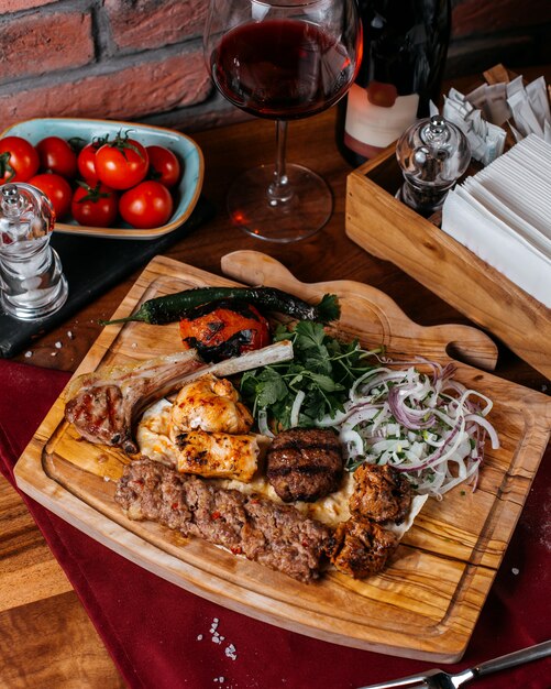 Draufsicht auf verschiedene Arten von Kebab mit roten Zwiebeln und Kräutern auf einem Holzbrett