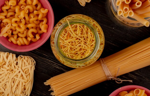 Draufsicht auf verschiedene Arten von Nudeln als Bucatini Cavatappi Spaghetti Fadennudeln Tagliatelle und andere auf Holzoberfläche