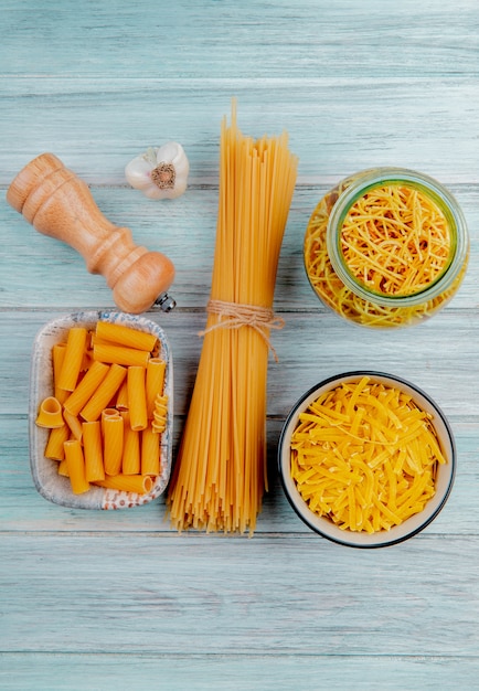 Kostenloses Foto draufsicht auf verschiedene arten von nudeln als tagliatelle spaghetti fadennudeln ziti und andere mit knoblauchsalz auf holzoberfläche