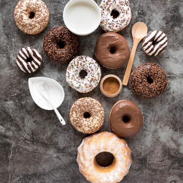 Draufsicht auf verschiedene Donuts mit Milch und Puderzucker