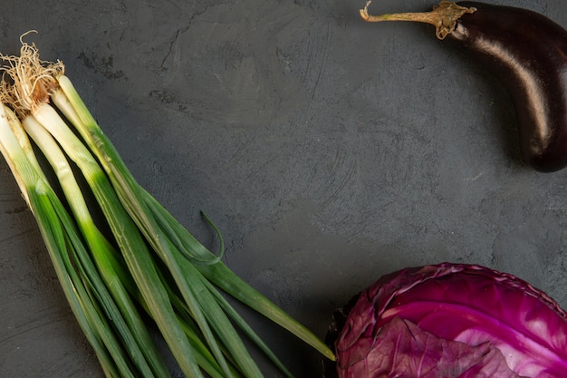 Draufsicht auf verschiedene Frischgemüse-Rotkohl-Auberginen und Frühlingszwiebeln mit Kopienraum auf dunklem j